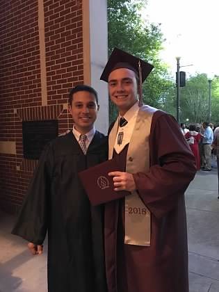 Paul in a graduation gown beside a graduating student holding a diploma.