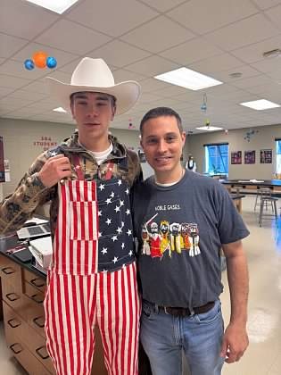 Paul in a Noble Gases t-shirt with a student dressed in a cowboy hat and flag overalls.